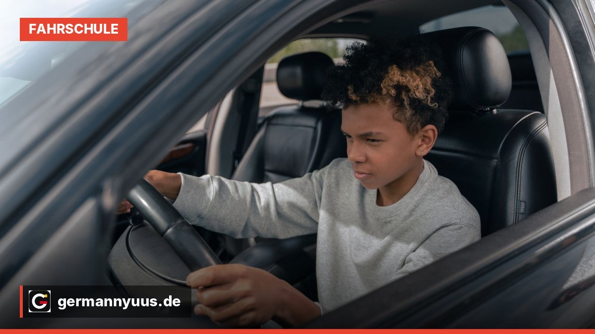 Ein Fahrschüler sitzt am Steuer eines Fahrschulautos, während der Fahrlehrer auf dem Beifahrersitz Anweisungen gibt.