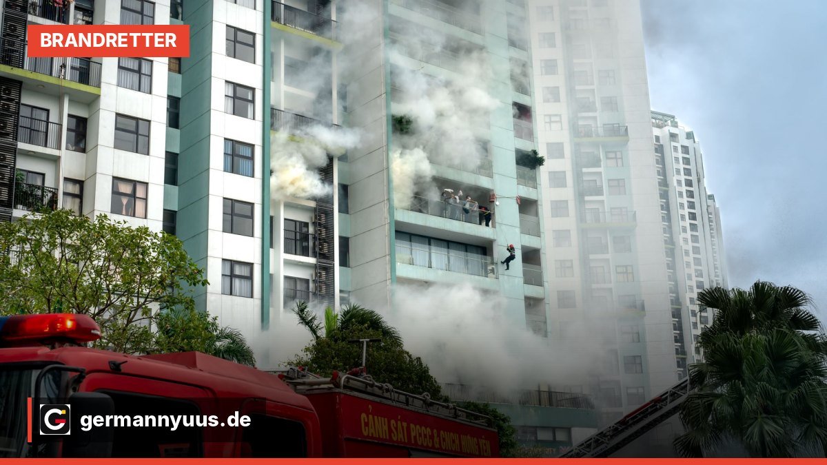 Feuerwehr mit Drehleiter vor einem brennenden Mehrfamilienhaus